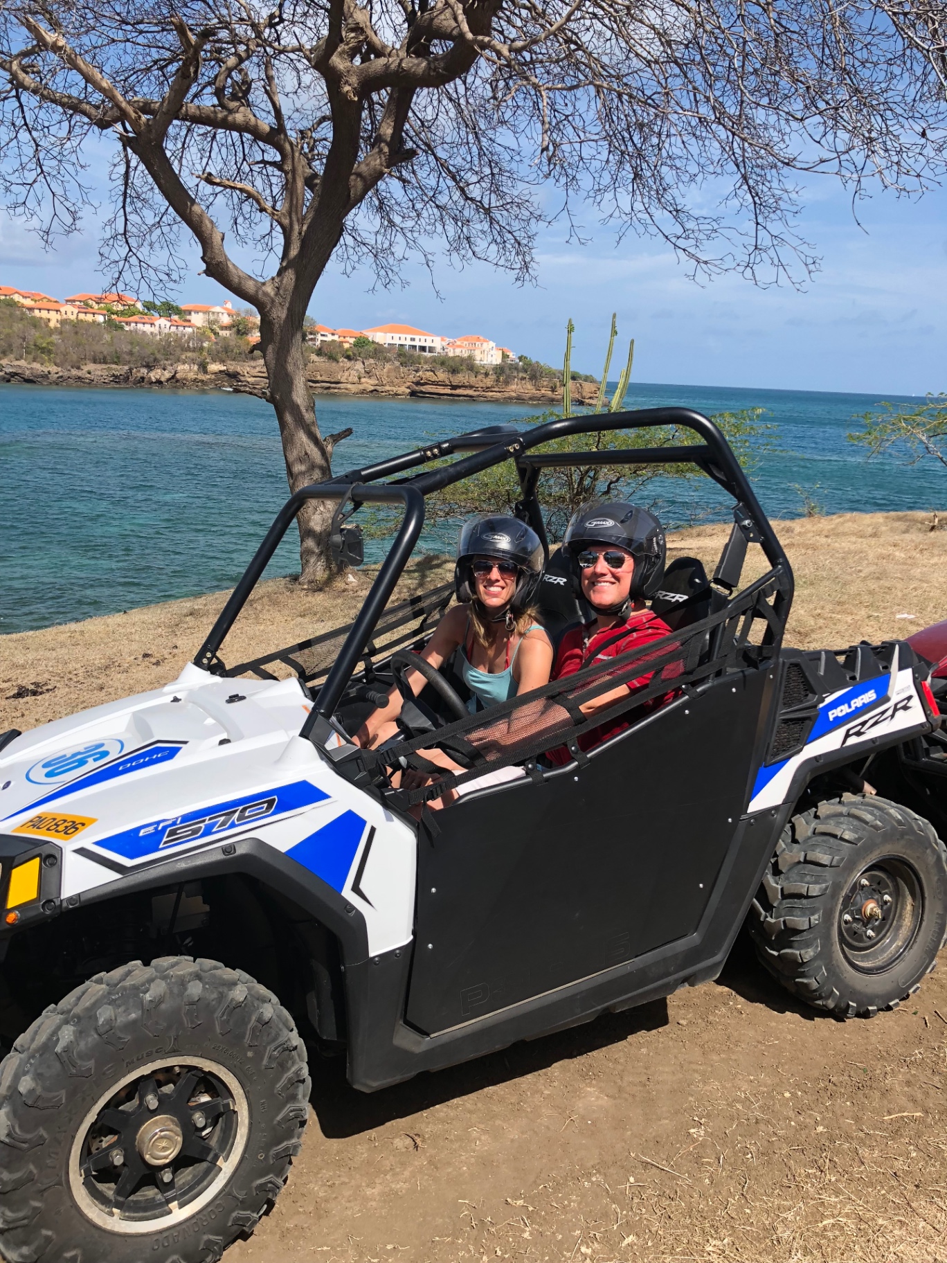 Adam and Jen in helmets in an off-road buggy by the sea