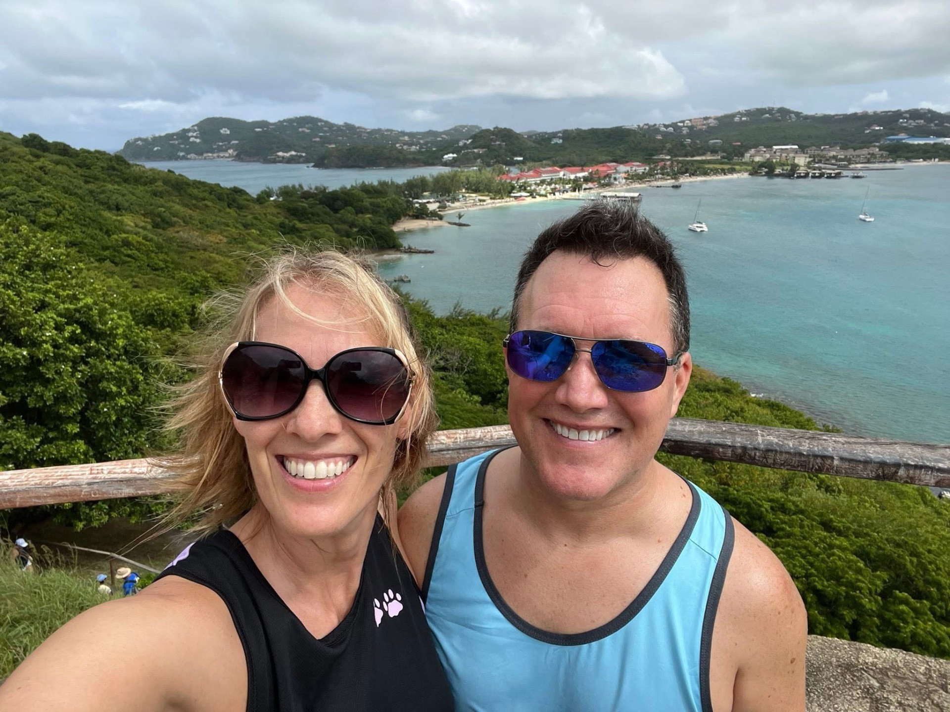 Adam and Jen Conway smiling at an island lookout above a turquoise bay