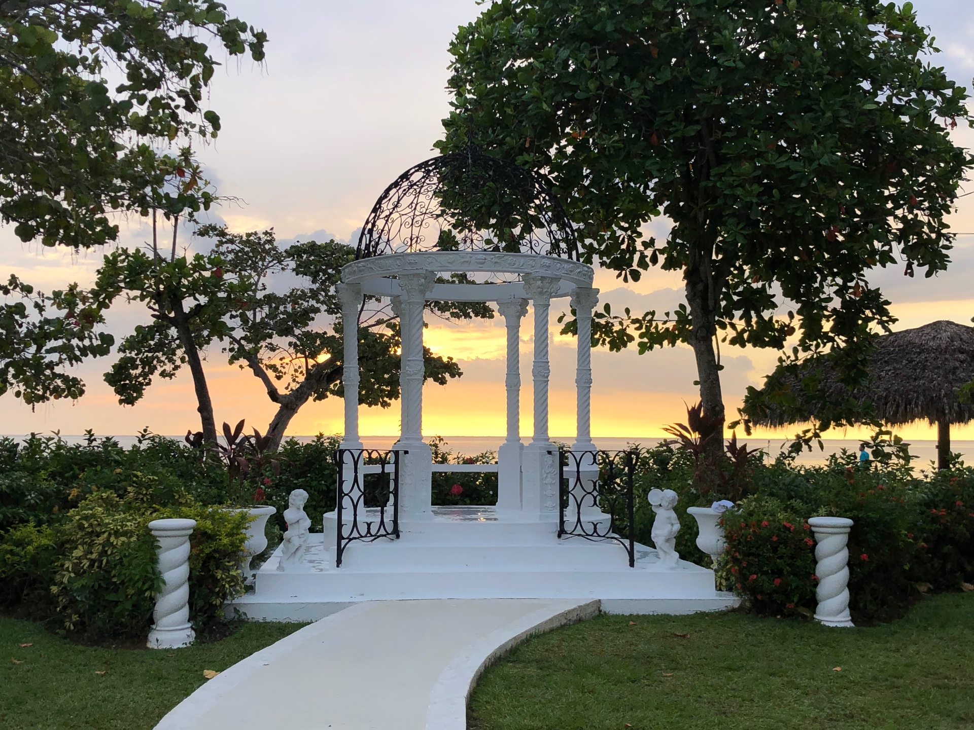An ornate white garden gazebo at sunset by the sea
