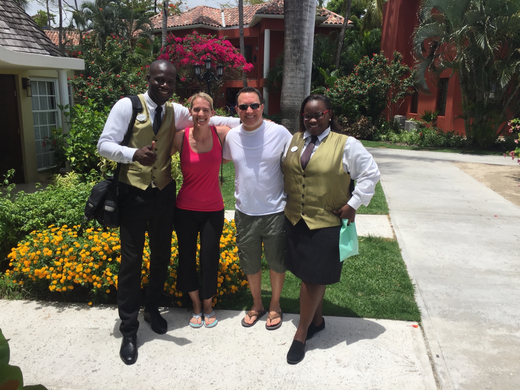 Adam and Jen Conway arm in arm with two Sandals resort staff members on a resort pathway