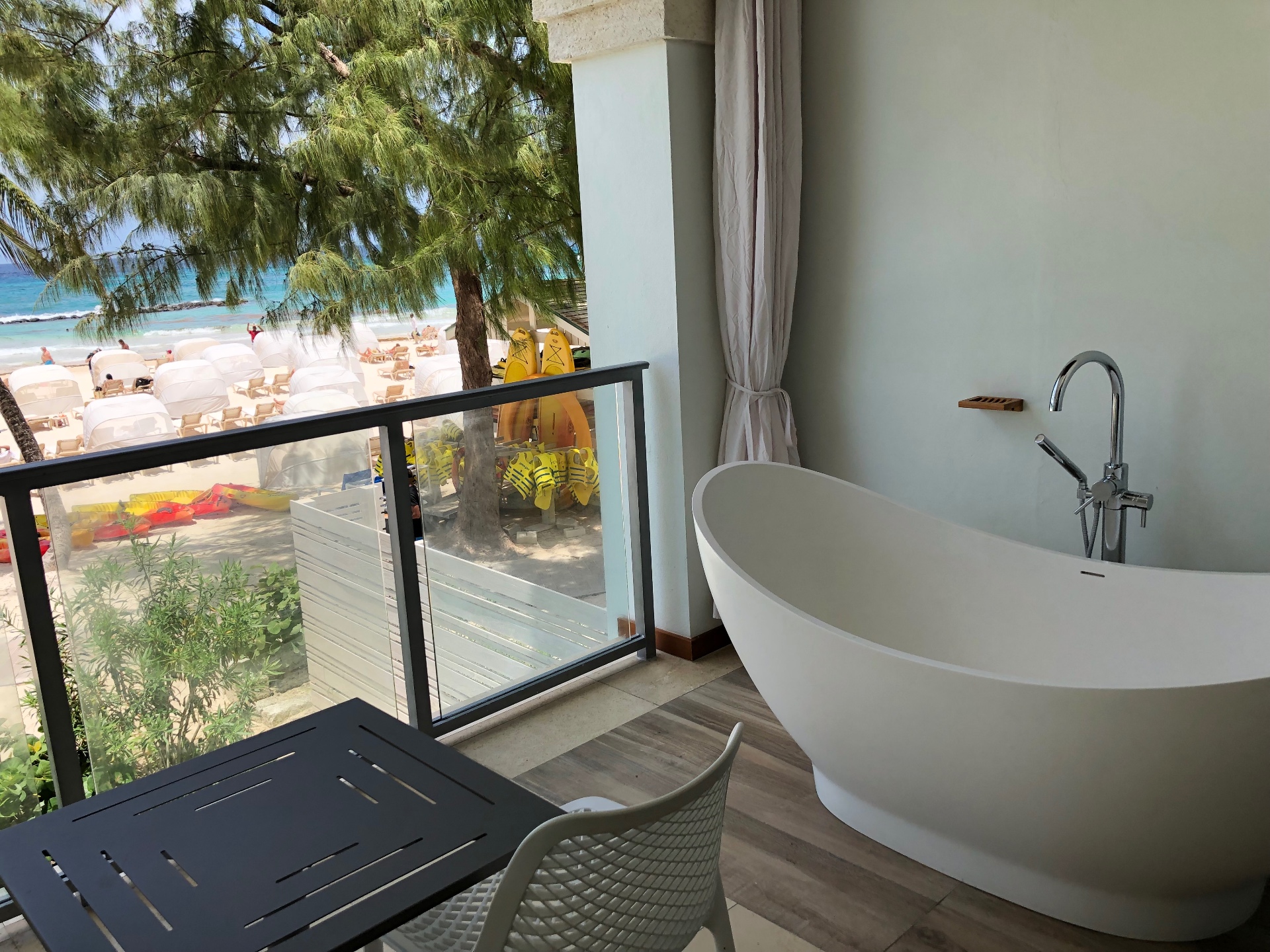 A freestanding soaking tub on a balcony overlooking the beach
