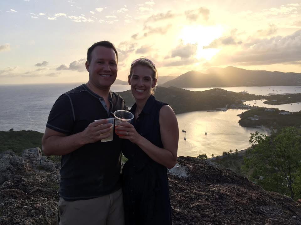 Adam and Jen Conway toasting at sunset above a Caribbean harbor