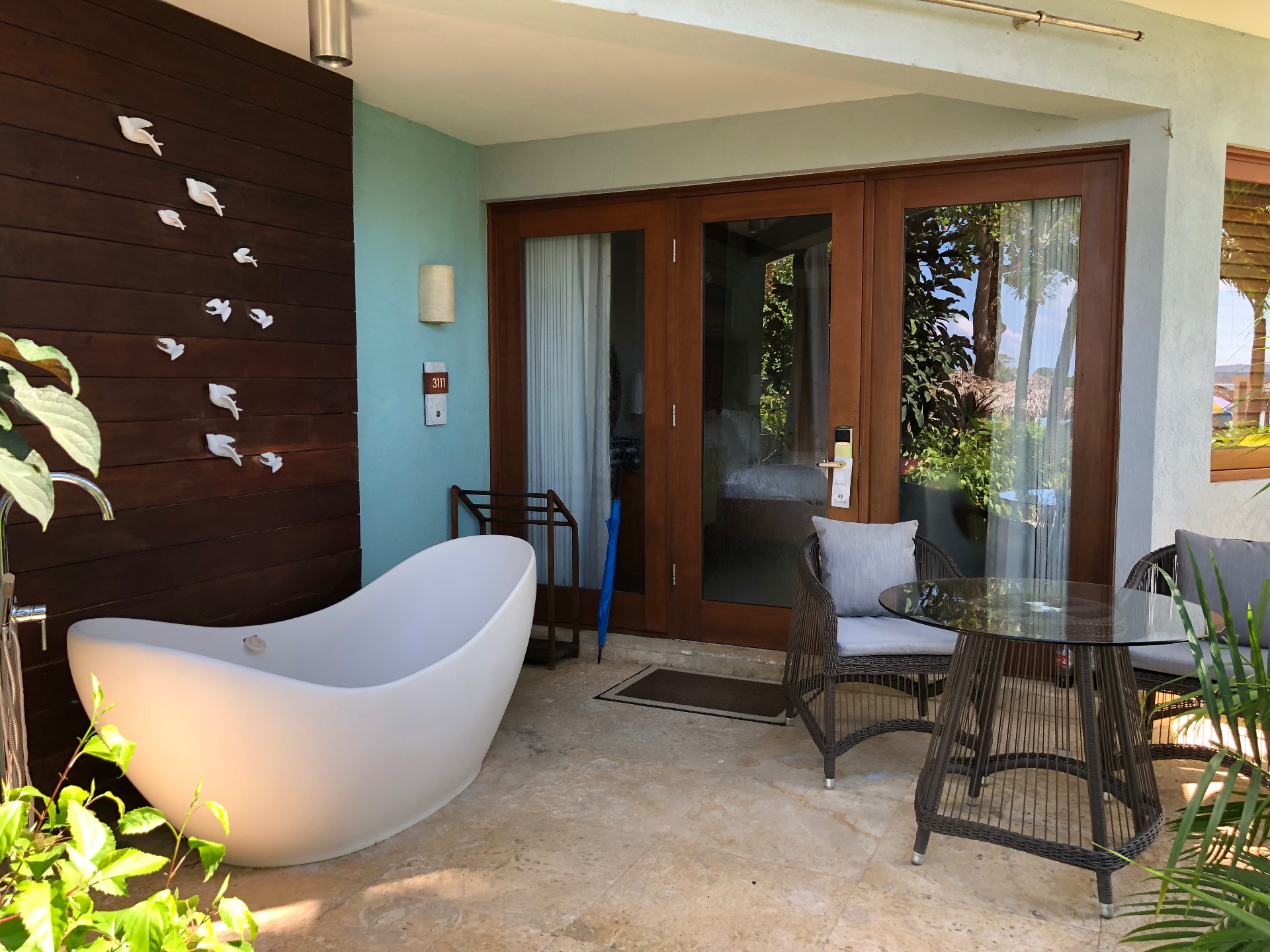 An outdoor soaking tub on a private patio beside a wooden wall with white birds